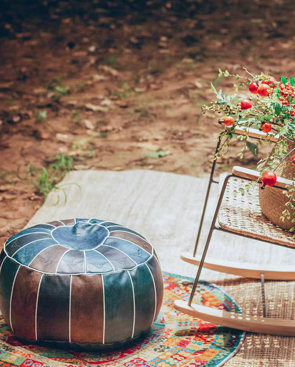 Blue faux leather pouf placed on rug outdoors with chair and decorative basket
