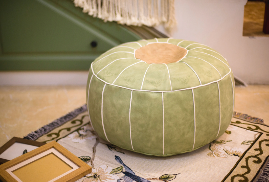 Light green faux leather pouf used as floor seating in cozy indoor space
