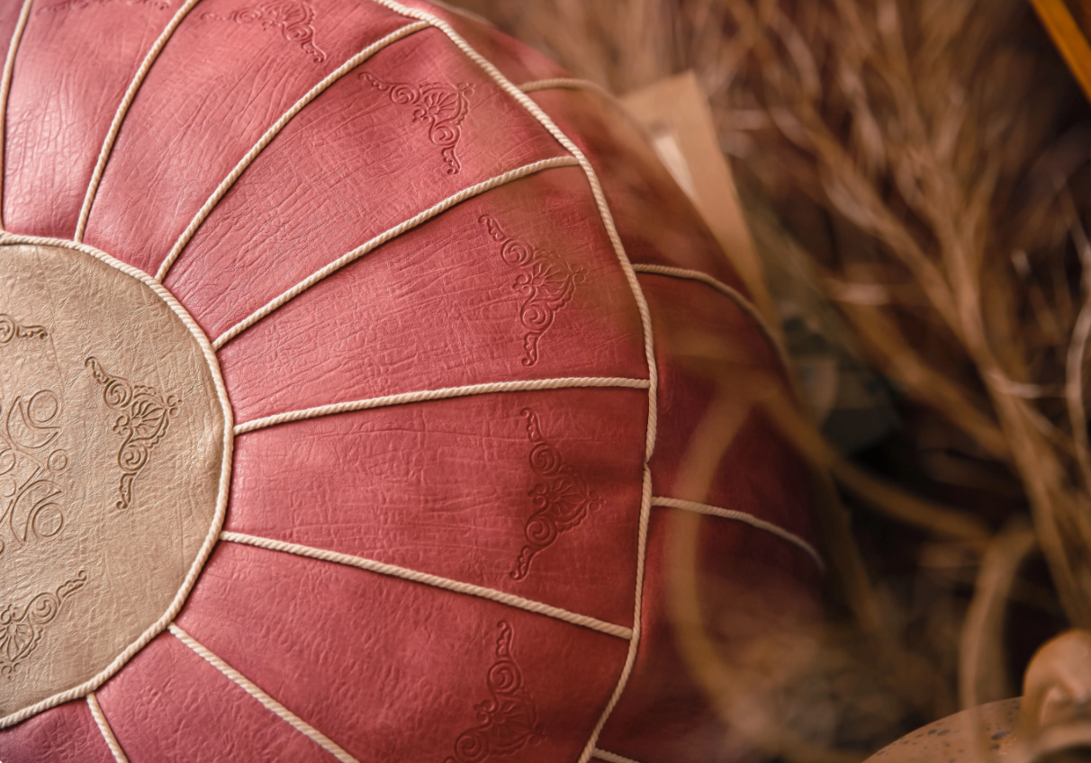Detailed view of pink faux leather pouf with embossed stitching and artisan design