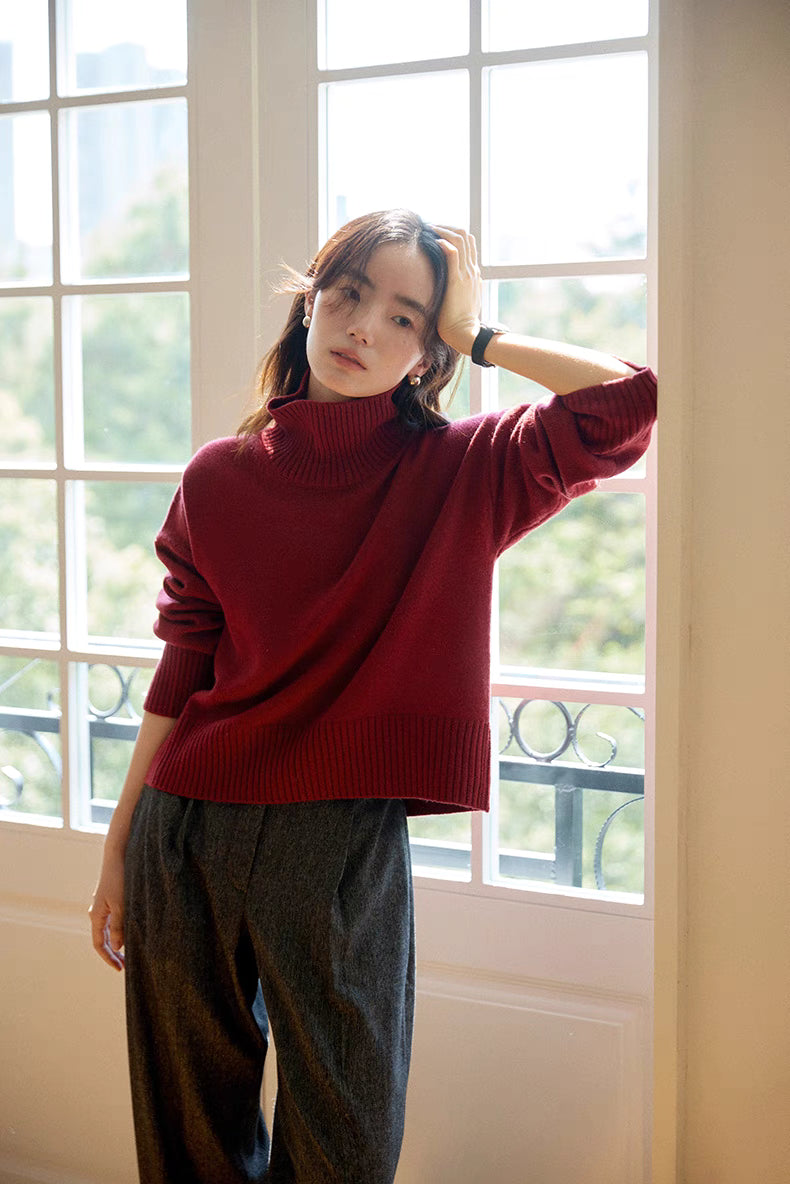 Model wearing red Bordeaux Wool-Cashmere Turtleneck Sweater standing by window with natural light showcasing elegant drape and ribbed details
