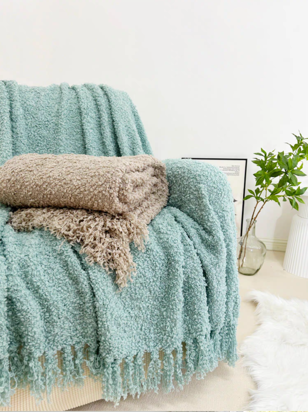 Blue loop knit throw blanket layered with gray blanket on armchair in cozy living space