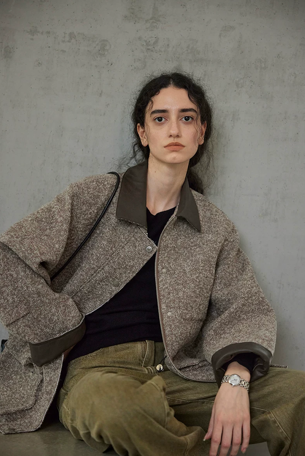 Seated view of a Brown wool tweed jacket showing the zip front, snap placket, and leather-look collar