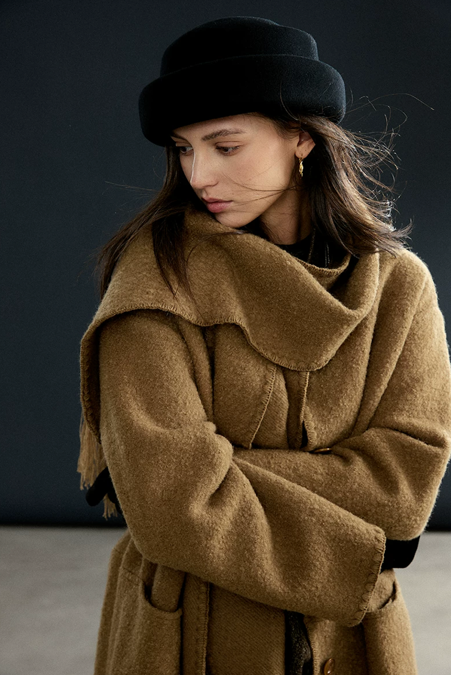 Close-up of a Camel bouclé wool coat and matching scarf showing the blanket-stitch edging