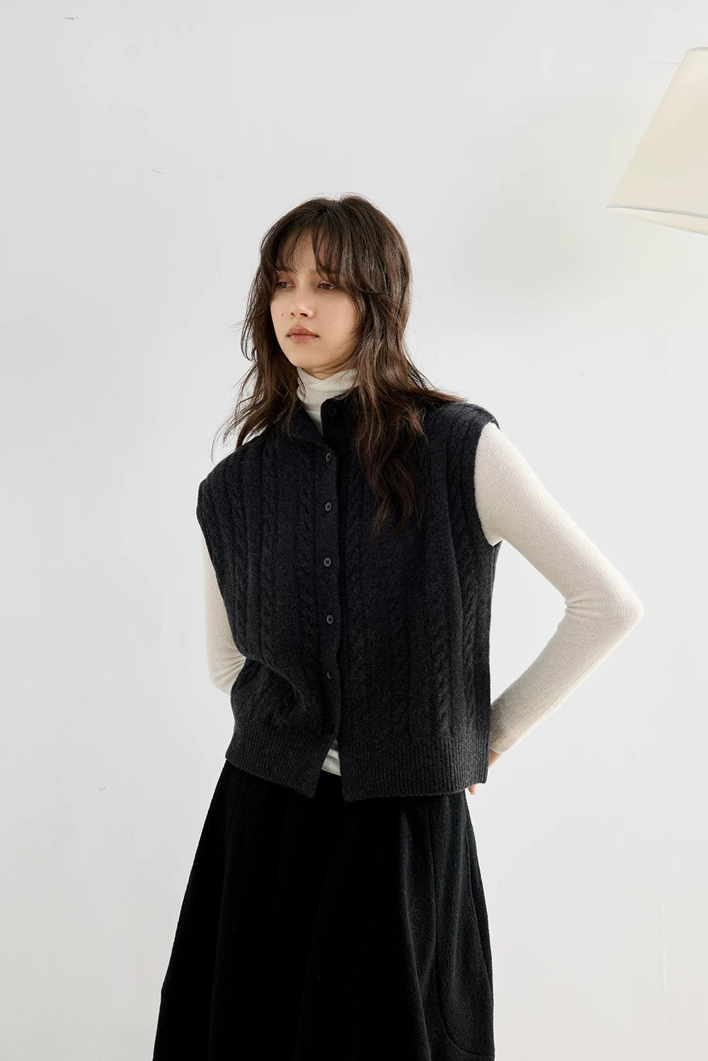 Model in Charcoal Gray stand-collar cable knit vest with hands behind her back