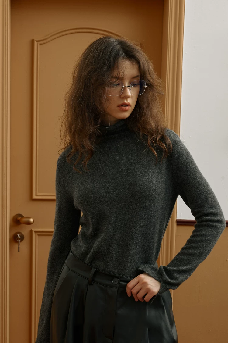 Charcoal pure cashmere turtleneck with rolled collar tucked into black pleated trousers