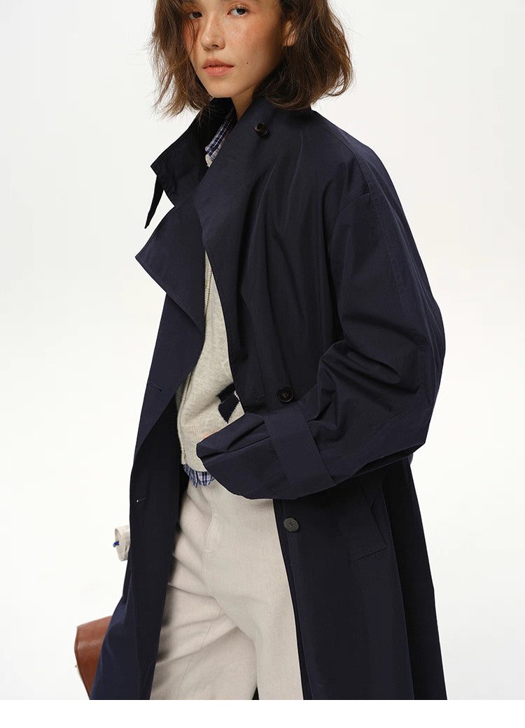 Three-quarter close-up of deep navy trench showing structured lapel and sleeve strap.