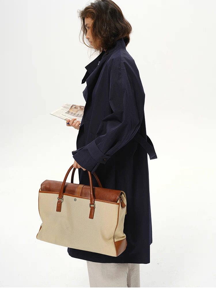 Side view of deep navy trench paired with canvas-leather bag, highlighting long silhouette.