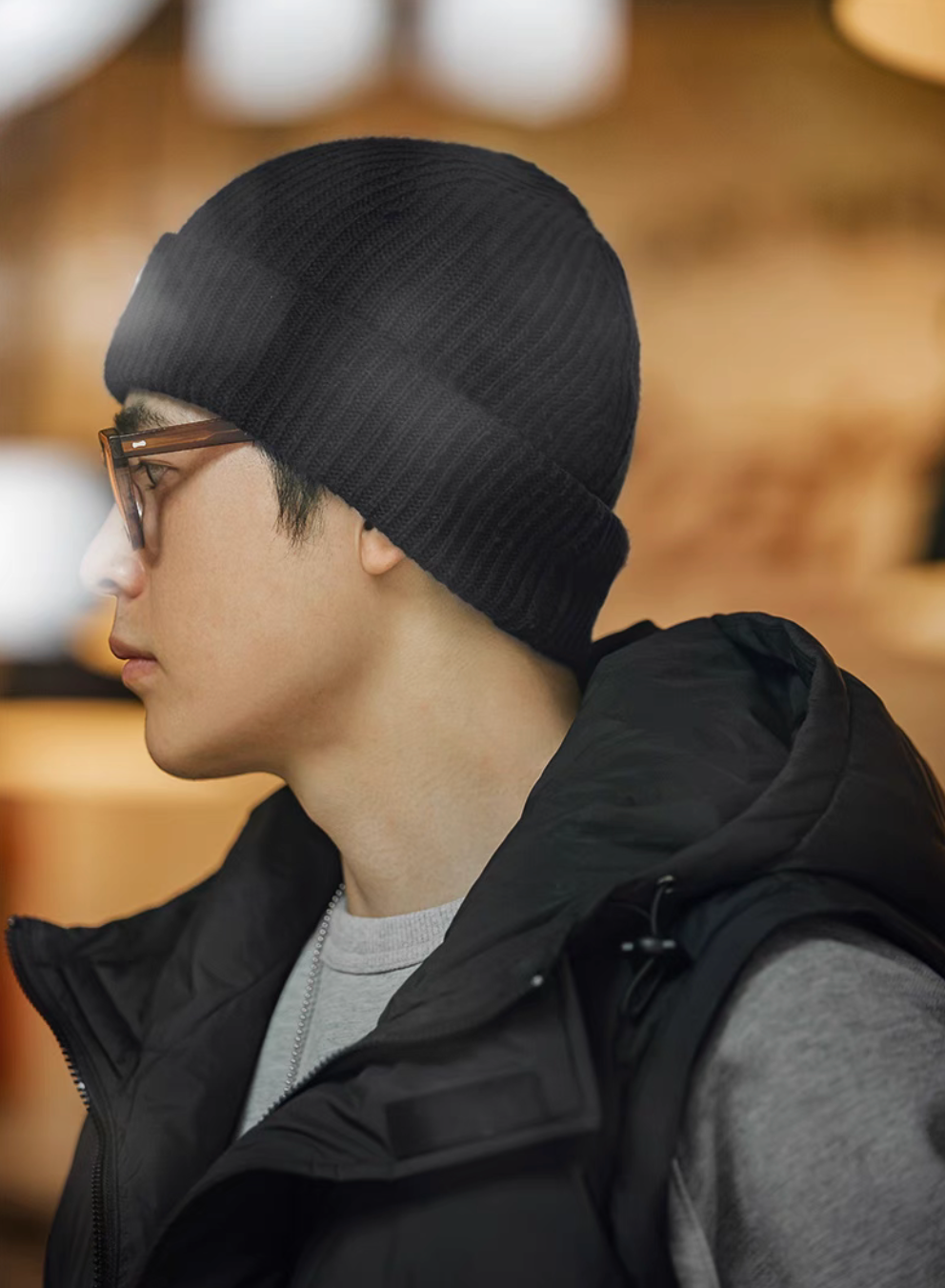 Side profile of model wearing Classic Ribbed Knit Beanie with Logo Detail in navy blue paired with casual layered outfit