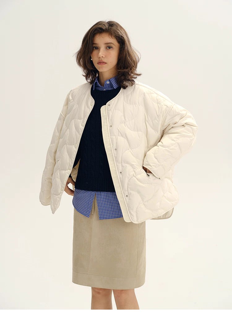 Model wearing ivory white quilted down jacket over navy sweater and check shirt.