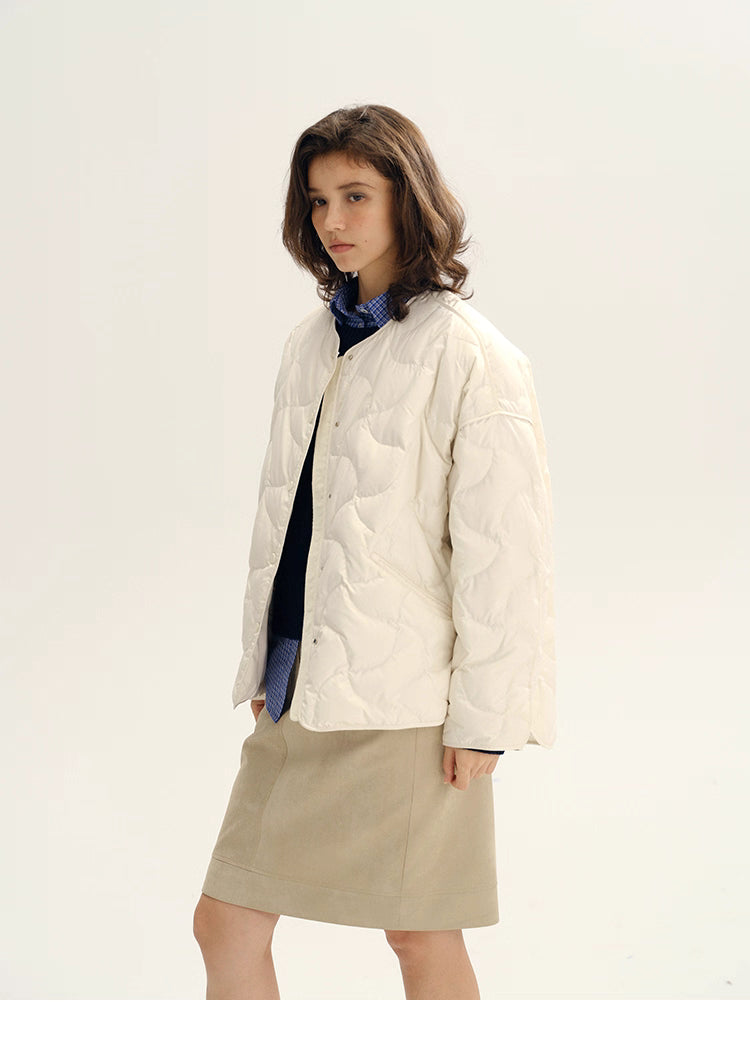 Three-quarter view of ivory quilted down jacket highlighting relaxed H-line silhouette.