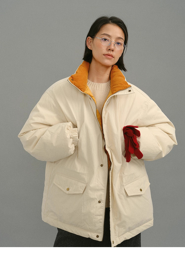 Model wearing a cream yellow down coat with mustard lining, holding red gloves in a front-facing pose.