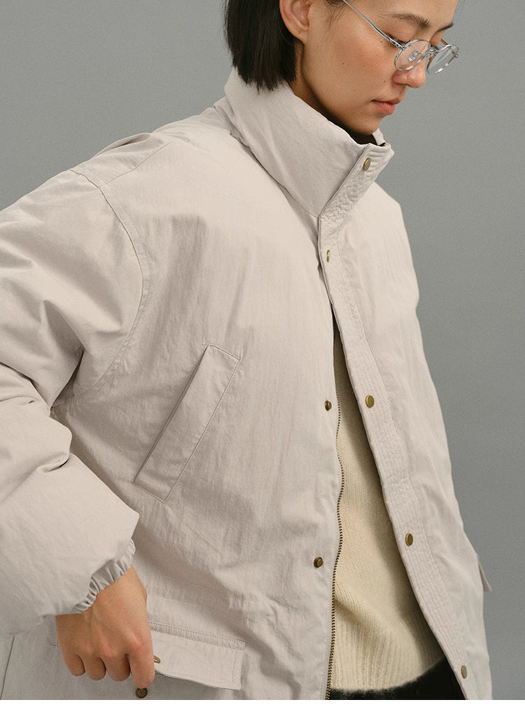 Close-up of light greige coat highlighting the tall stand collar and matte cotton-blend texture.