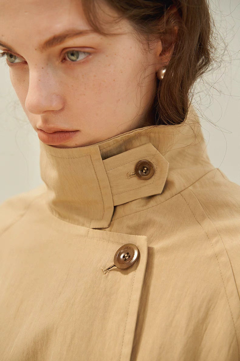 Close-up of light brown trench coat lapel collar with button detail and textured fabric