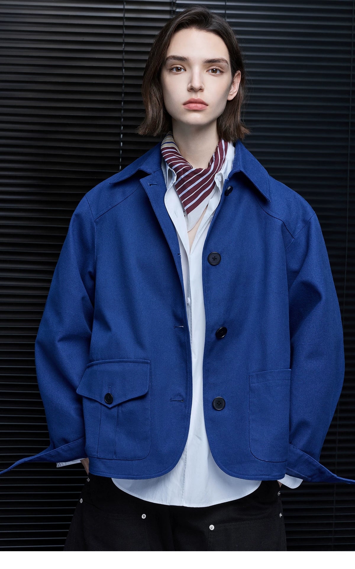 Close-up of a Cobalt Blue boxy chore jacket with dark contrast buttons and extended cuff tabs
