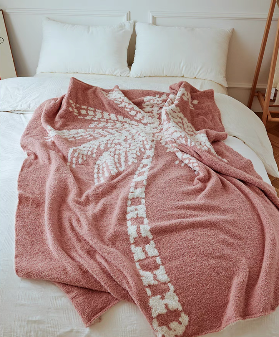 Pink coconut tree throw blanket spread across bed creating cozy and stylish bedroom look