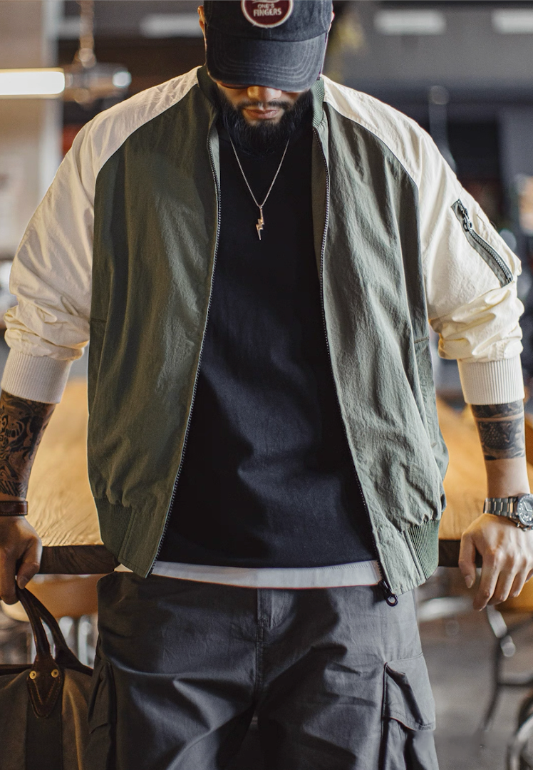 Man wearing green and cream MA-1 bomber jacket indoors showing modern street look