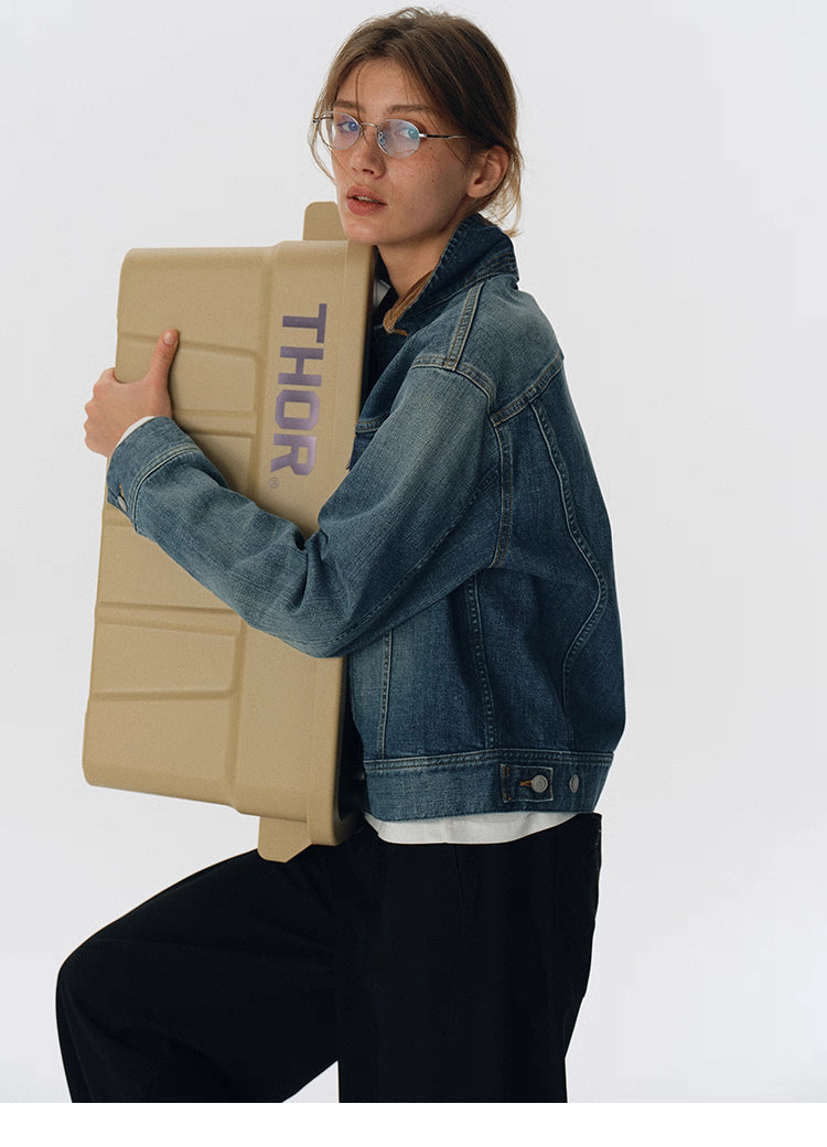 Side view of denim jacket with brown corduroy collar as model holds beige THOR storage box