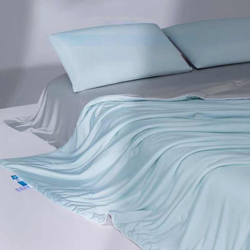 Blue and gray cooling antibacterial summer quilt draped over a bed with matching pillows, showing smooth breathable cooling fabric.