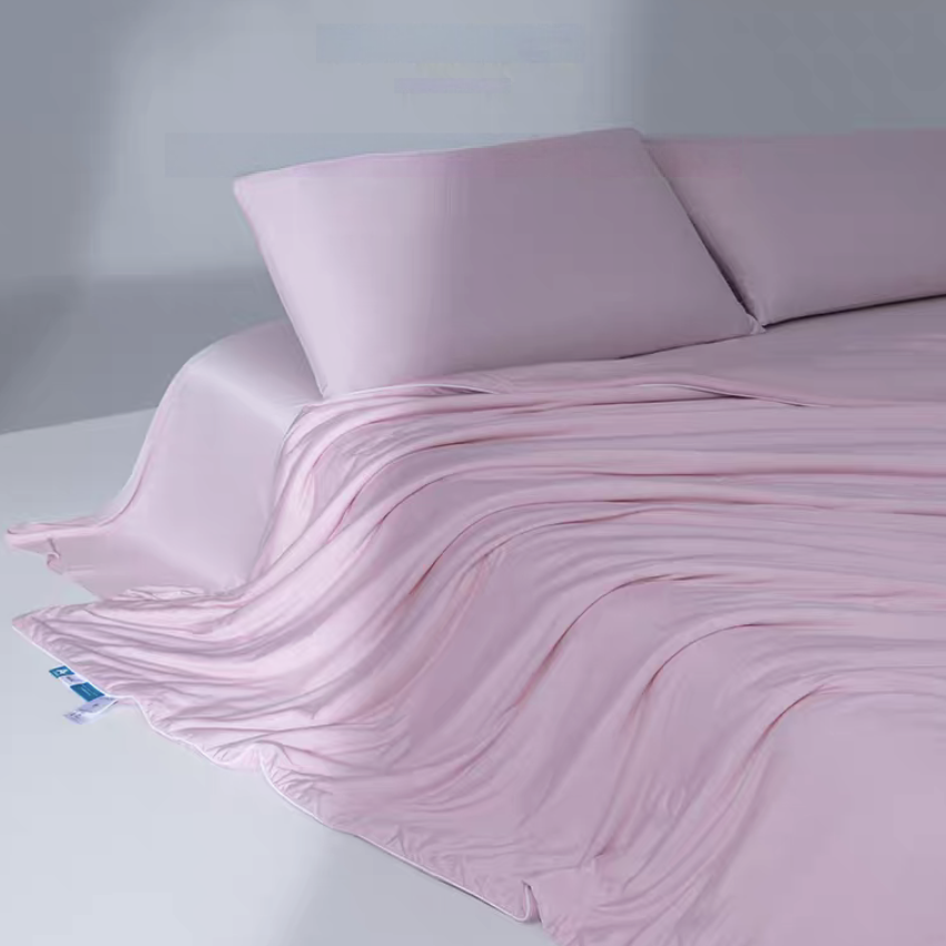 Lilac pink cooling antibacterial summer quilt layered over a bed showing lightweight breathable cooling fiber material.