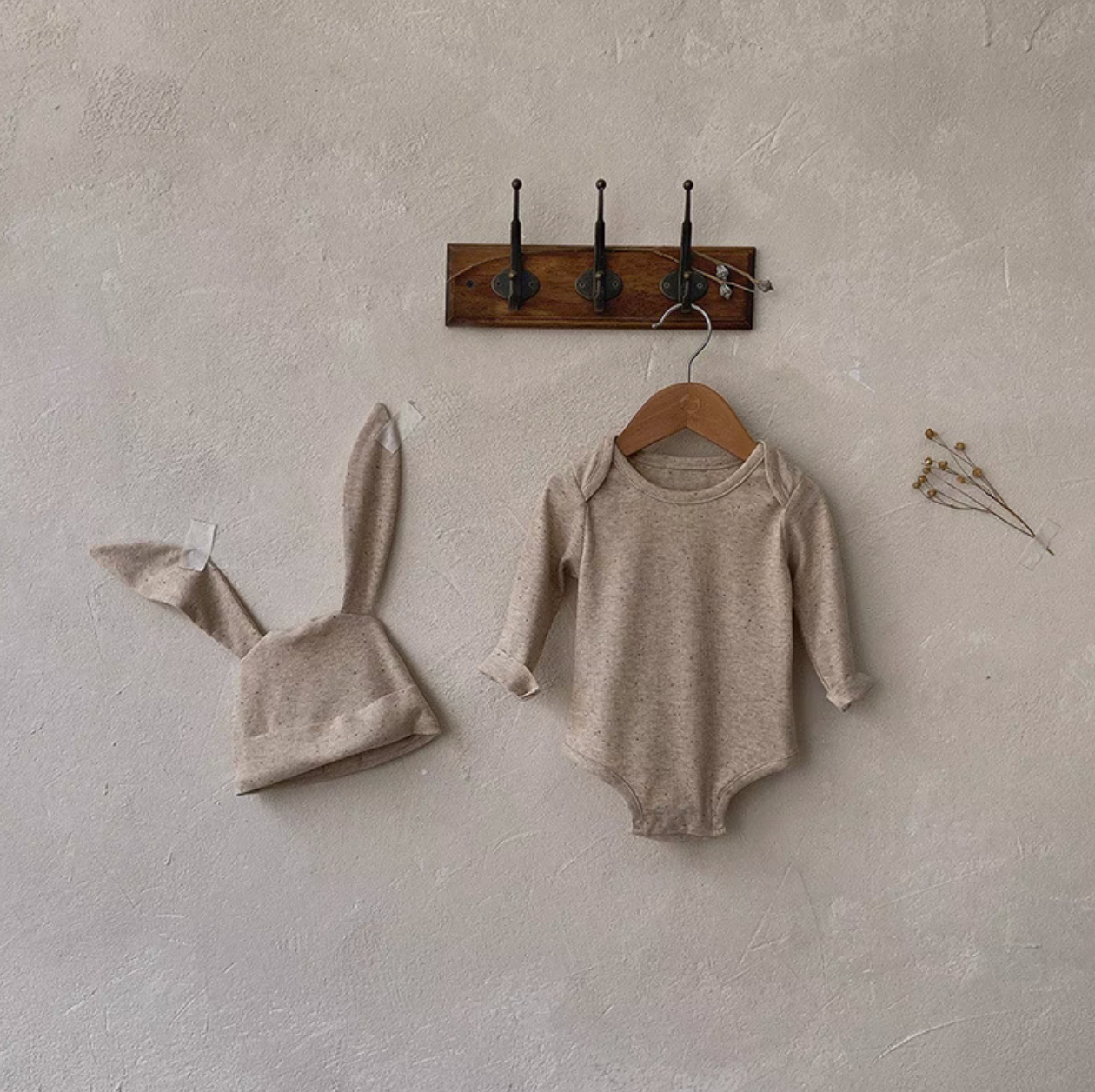 Oatmeal beige long sleeve baby bodysuit with bunny ear hat minimal wall hanging display