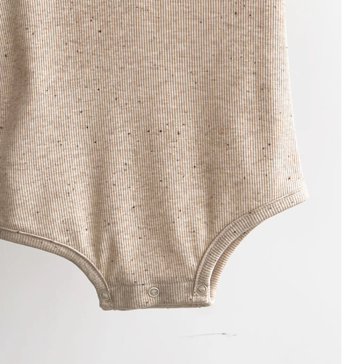 Close-up oatmeal beige short sleeve baby bodysuit bottom with ribbed cotton and snaps