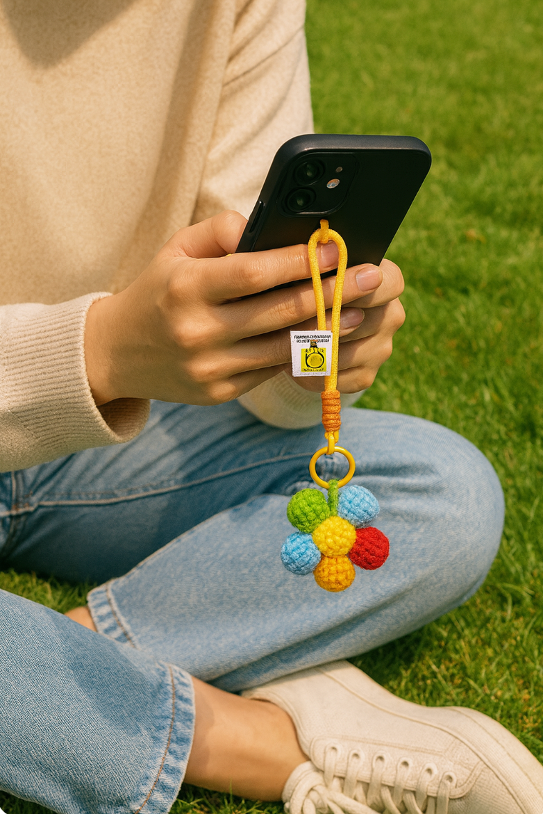 Crochet flower keychain attached to phone case, colorful rope loop.