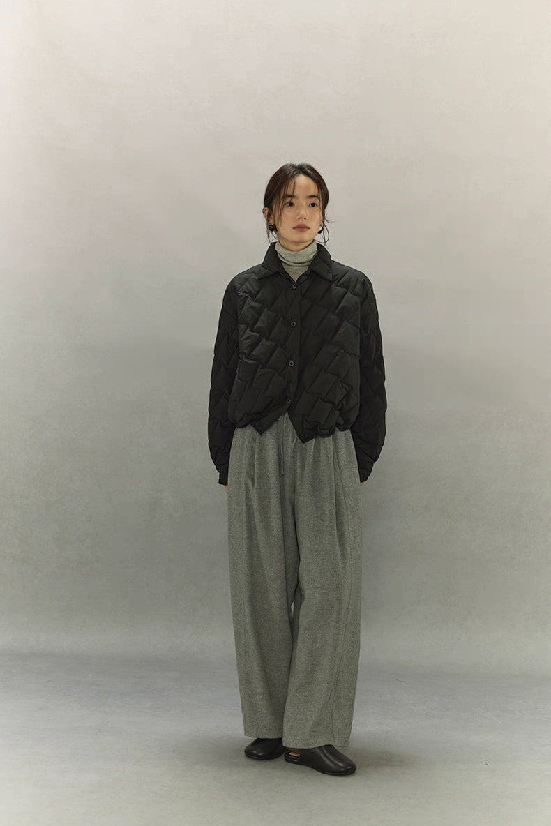 Full-body front view of black cropped quilted goose down shirt jacket with grey wide-leg pants and black shoes.
