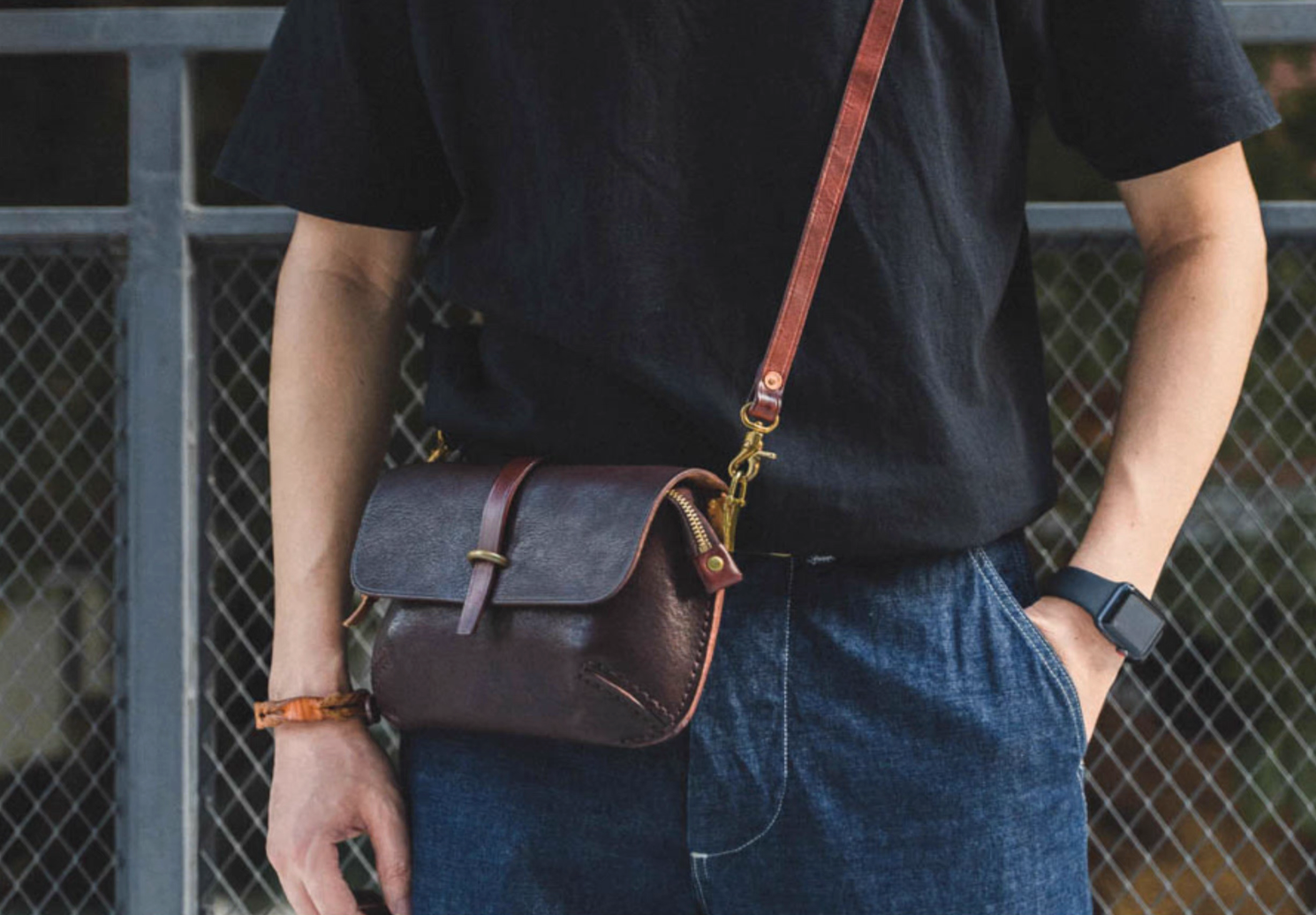 Man standing wearing minimal Italian full-grain leather crossbody bag with brass hardware