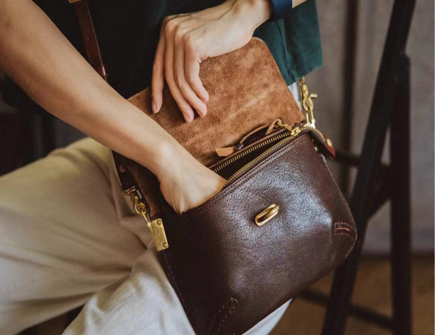 Person opening handcrafted Italian full-grain leather bag showing suede lining