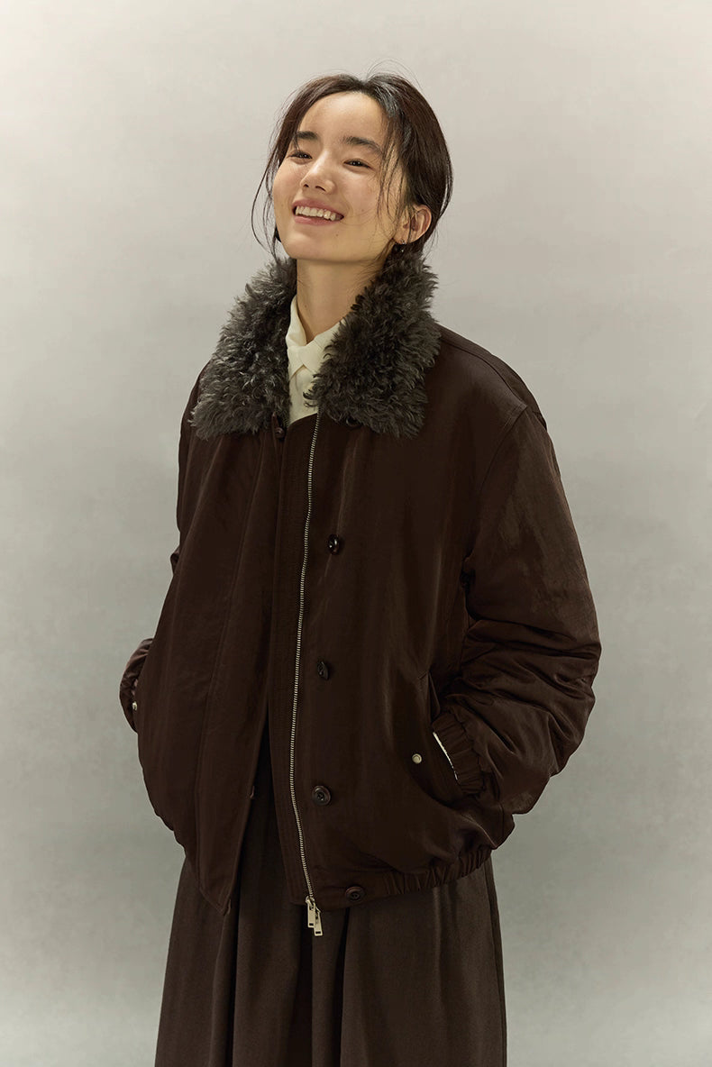 Smiling model in dark coffee brown sherpa-collar down jacket against neutral background