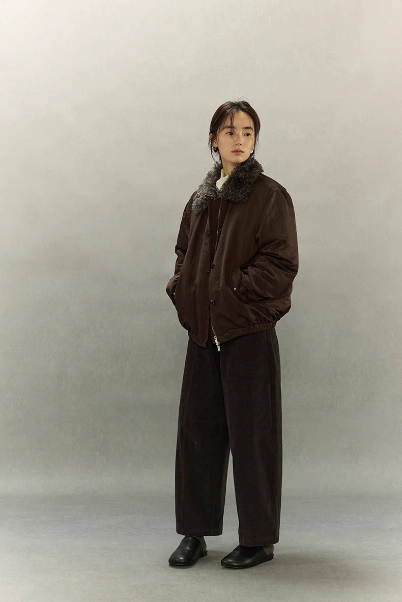 Angled full-body view of model wearing dark coffee brown sherpa-collar down jacket and black shoes