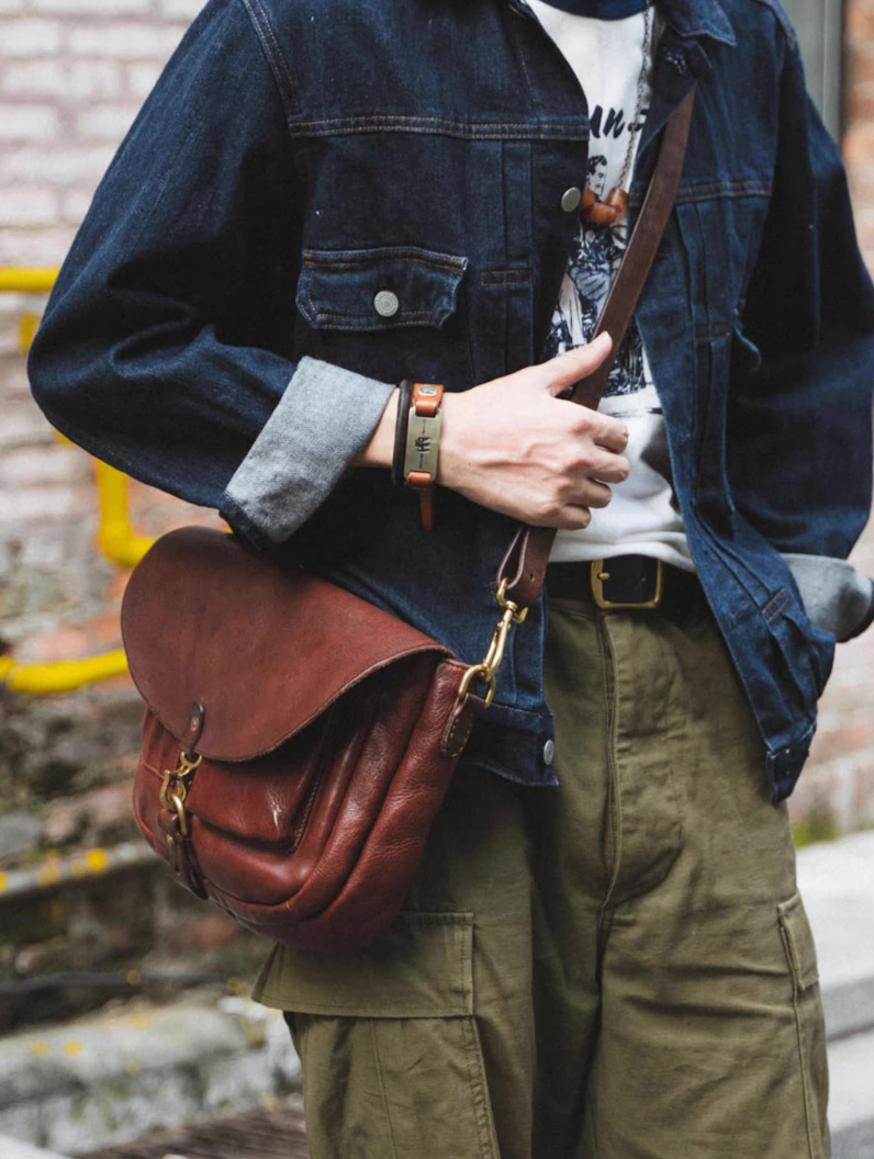 Vintage red-brown leather shoulder bag styled with denim and cargo pants outdoors