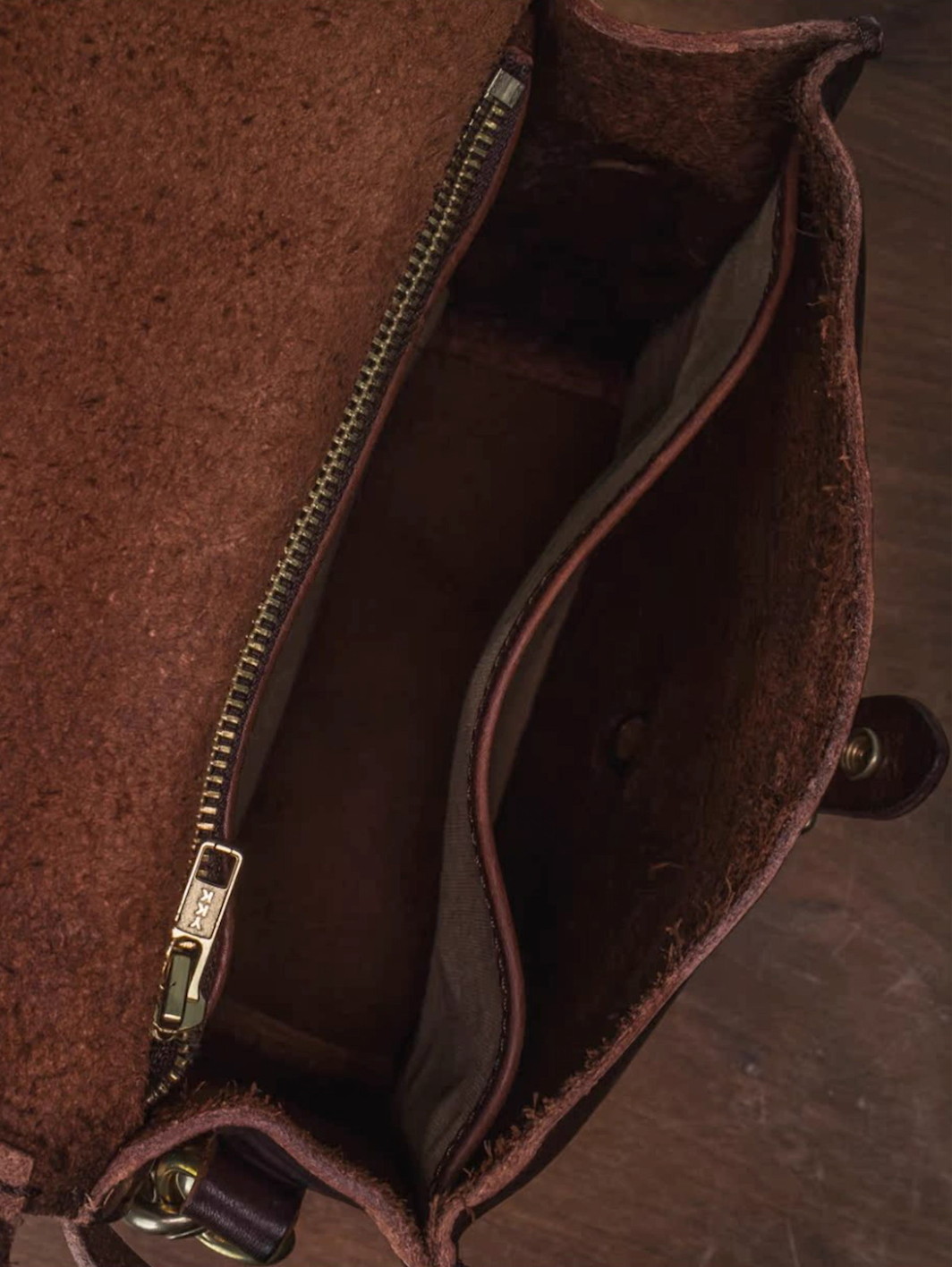 Inside view of artisan leather satchel showing YKK zipper and divider pocket