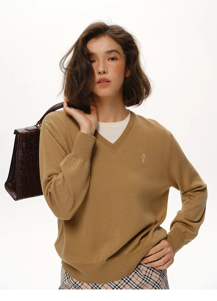 Close-up of Camel Brown merino wool V-neck sweater showing embroidered chest detail