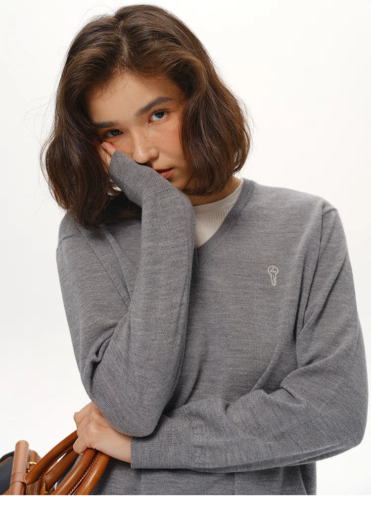 Close-up of Heather Gray wool V-neck sweater showing soft texture and embroidered icon