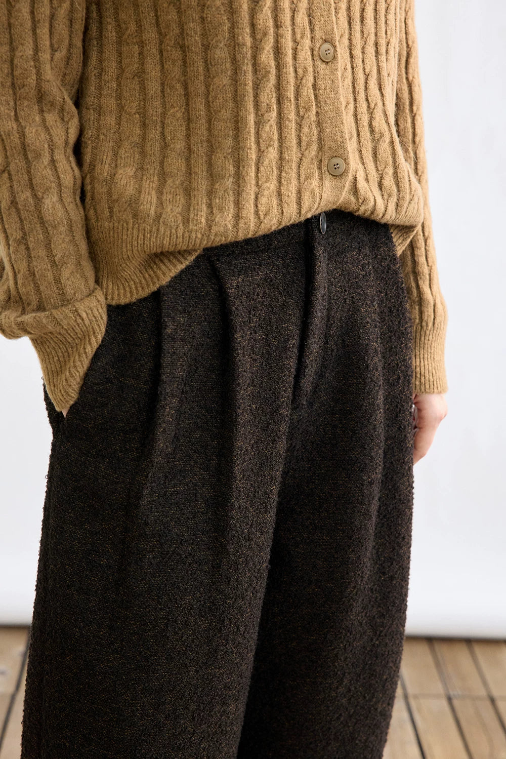 Close-up of Dark Brown bouclé trousers showing front pleats, button waist, and side pocket