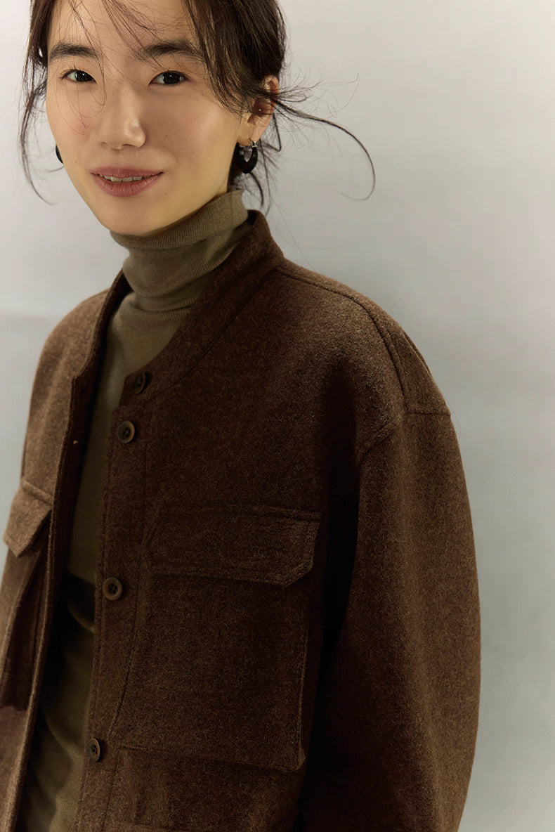 Close-up of woman smiling in dark coffee alpaca wool field jacket showing collar and chest pocket detail