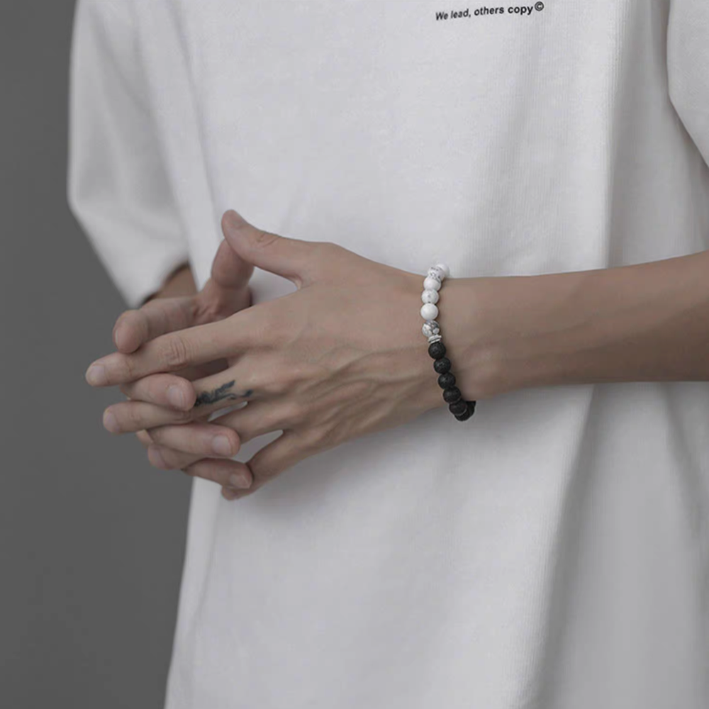 Black and white cracked lava stone bracelet worn on wrist showing dual-tone bead design symbolizing day and night