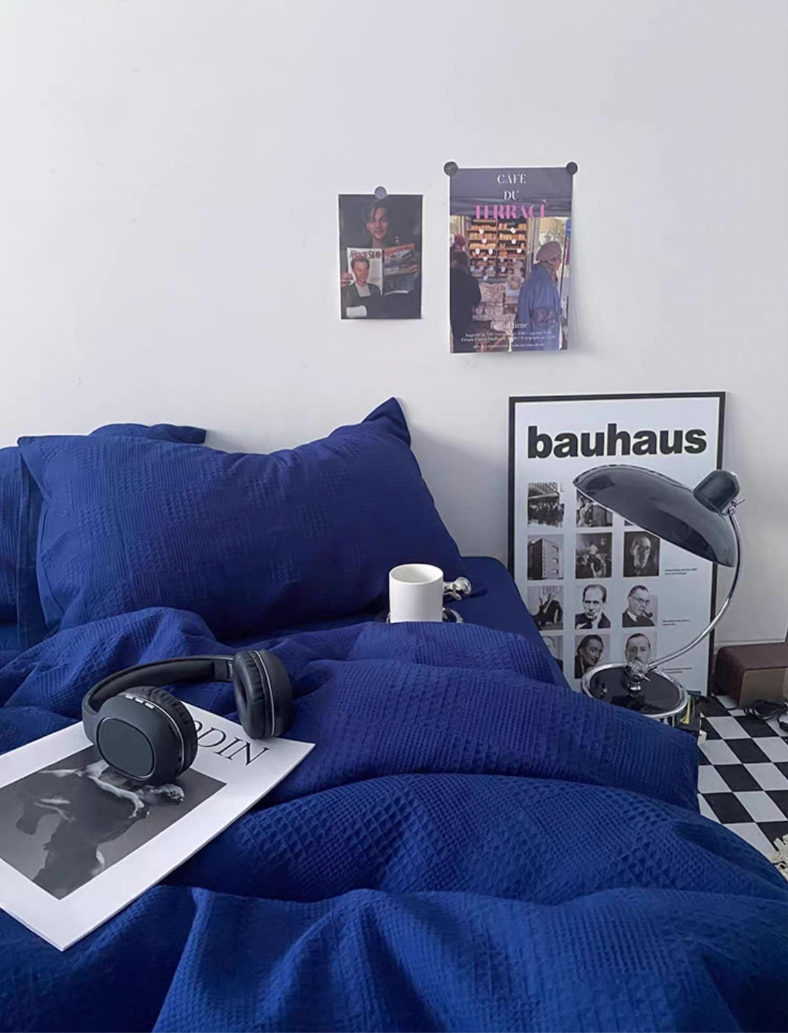Royal blue diamond-waffle jacquard duvet cover set with pillows, desk lamp and wall posters in a stylish bedroom.