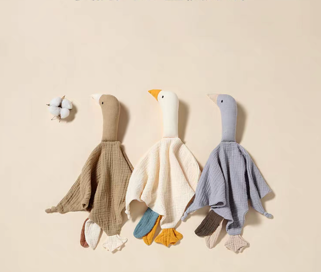 Duck lovey teething toys in multiple colors arranged side by side including khaki, cream, gray, and soft tones
