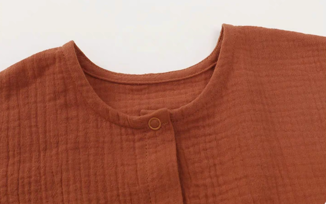 Close-up of orange red romper neckline and button detail