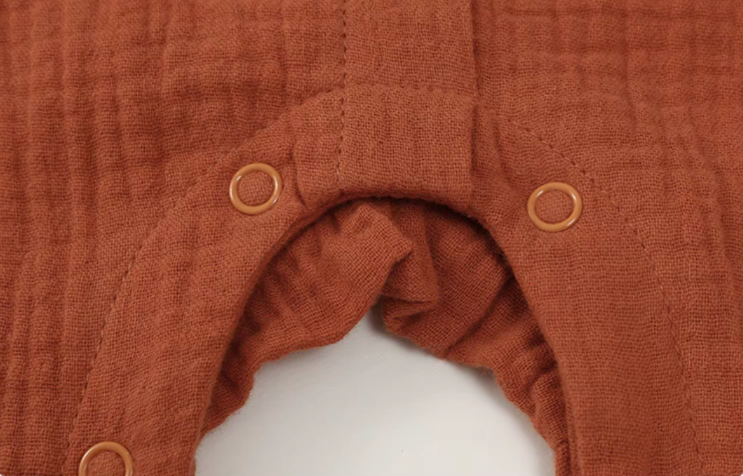 Close-up of orange red romper bottom snap buttons for easy diaper change