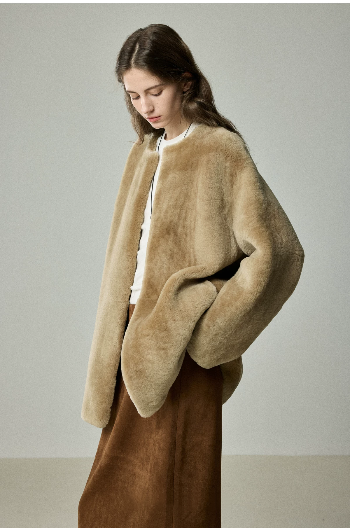Side view of camel shearling jacket showing dropped shoulders and softly rounded hem