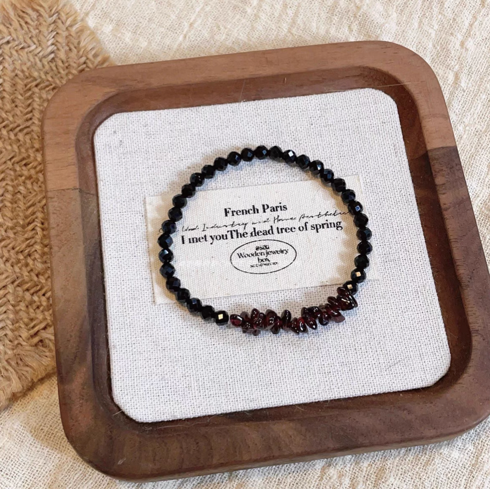 Black spinel bracelet with deep red garnet chip beads displayed on linen tray for elegant minimalist style