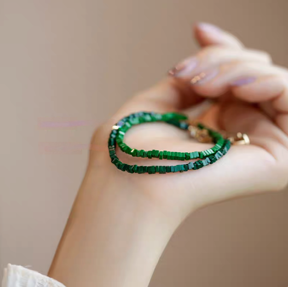 Moss green minimalist malachite bracelets layered together on hand for a stacked jewelry look