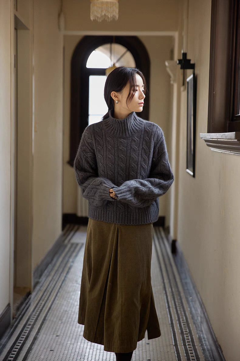 Full outfit view of dark gray cable-knit turtleneck sweater styled with skirt in hallway setting