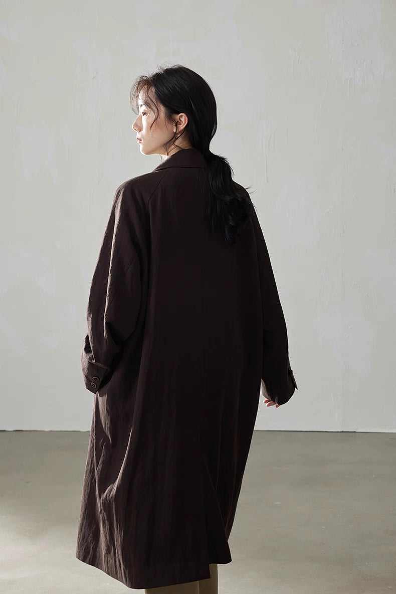 Back three-quarter view of the coffee brown fluid-drape Tencel trench coat, highlighting long straight back panel.