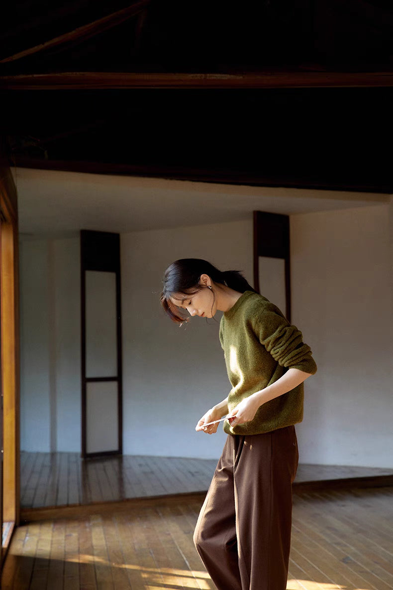 Full outfit view of cardamom green brushed wool sweater in minimalist interior showcasing relaxed silhouette