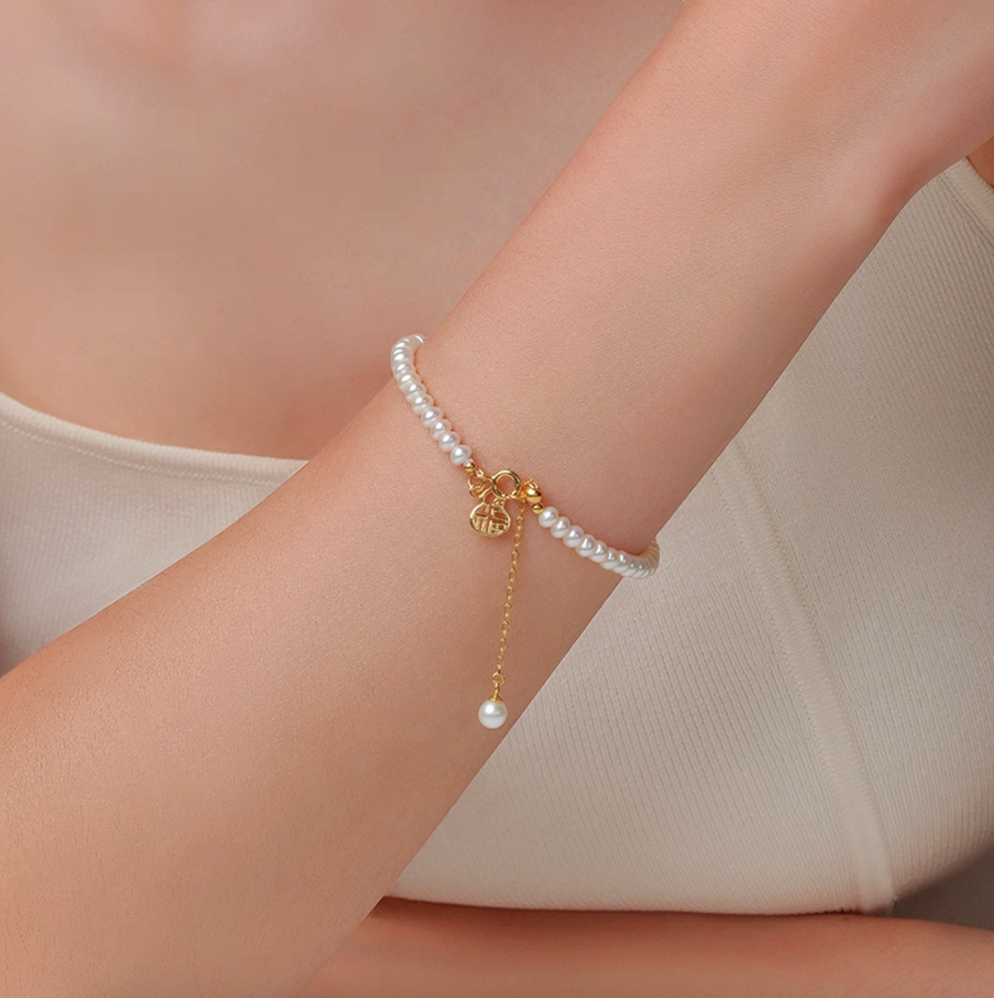 Model wearing freshwater pearl bracelet with gourd Fu charm and adjustable chain, delicate everyday jewelry.