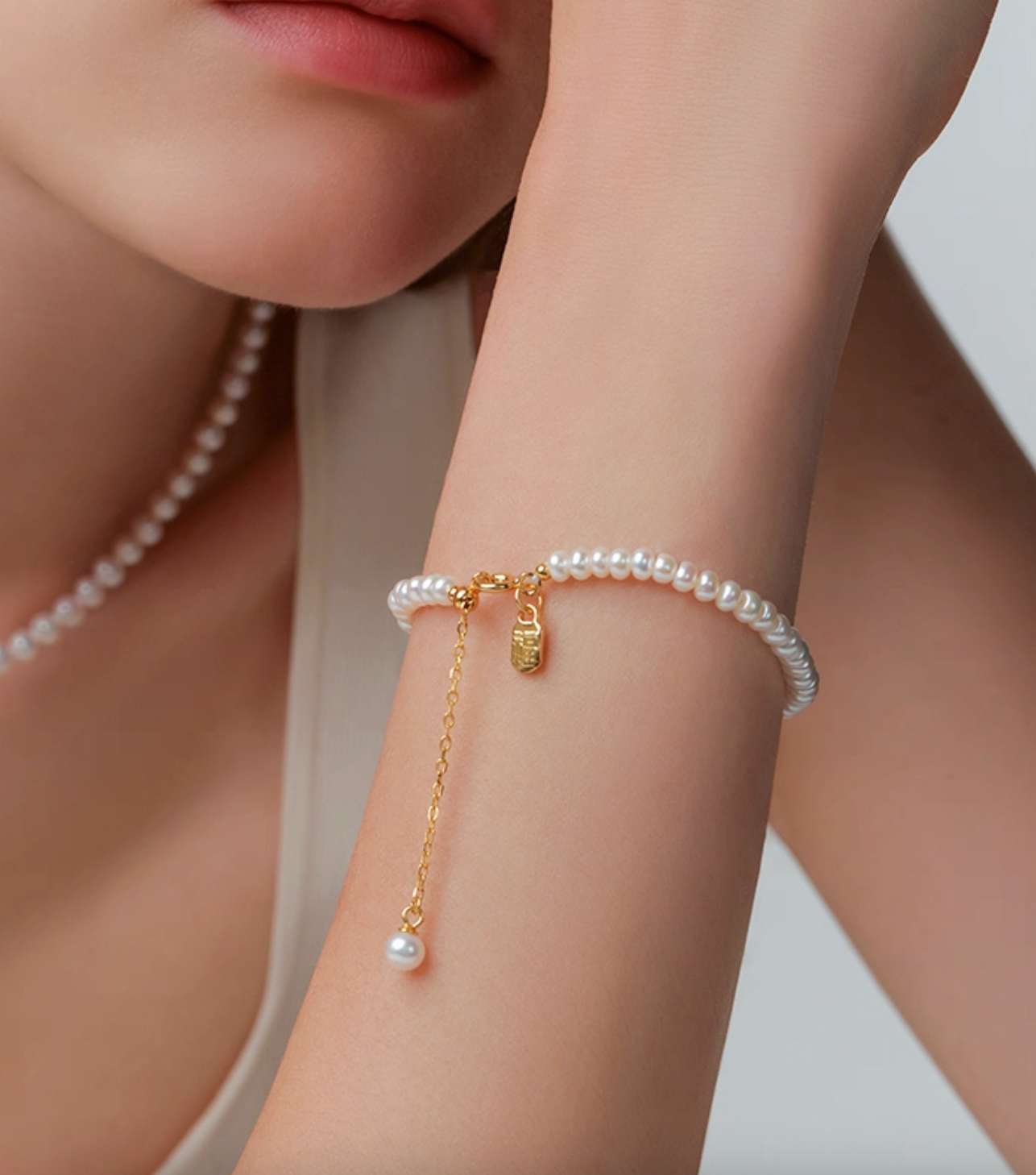 Close-up of pearl bracelet on wrist with Fu tag charm, adjustable chain, elegant gift for women.
